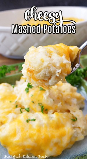 A bite of mashed potatoes sitting over a blue plate that is loaded with a servings of mashed potatoes.