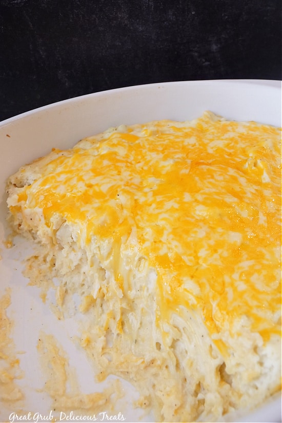 A white casserole dish loaded with mashed potatoes that are topped with melted cheese.
