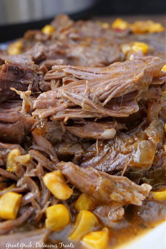 A close up photo of chuck roast sitting on top of corn.