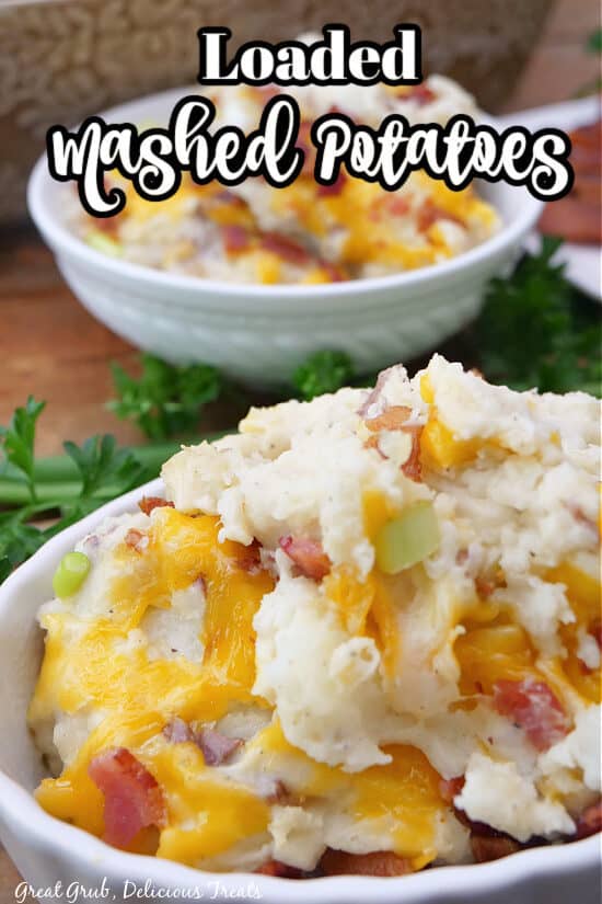 A white small oval bowl filled with a serving of loaded mashed potatoes.