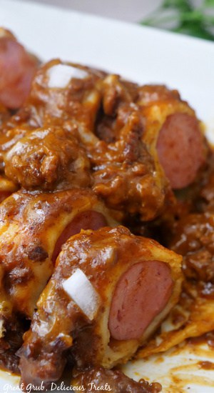 A white plate with chili cheese dogs cut into bite-size pieces.