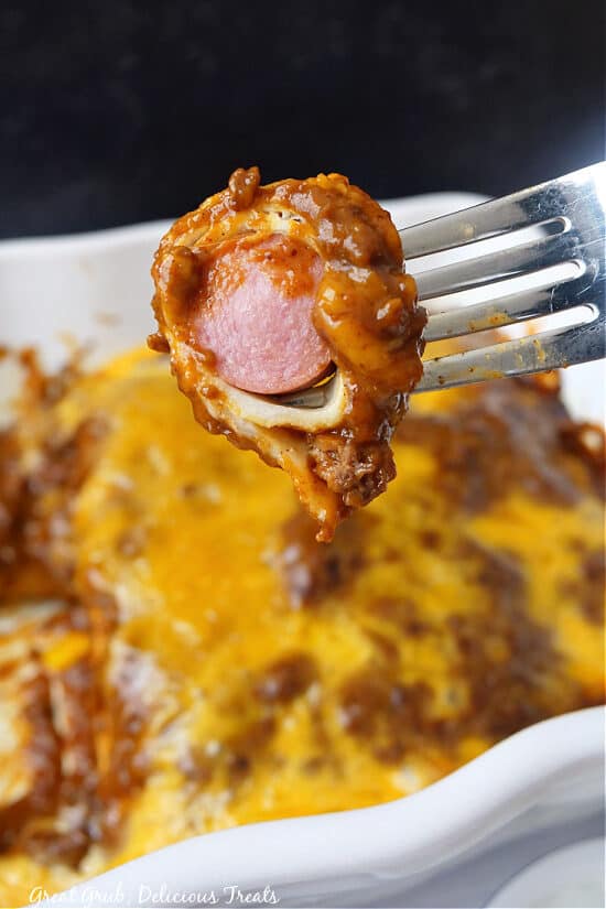 A close up of a bite of chili dog on a fork.