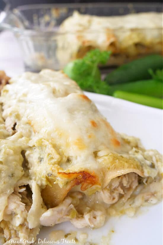 A close up of two chicken enchiladas Suizas on a white plate.