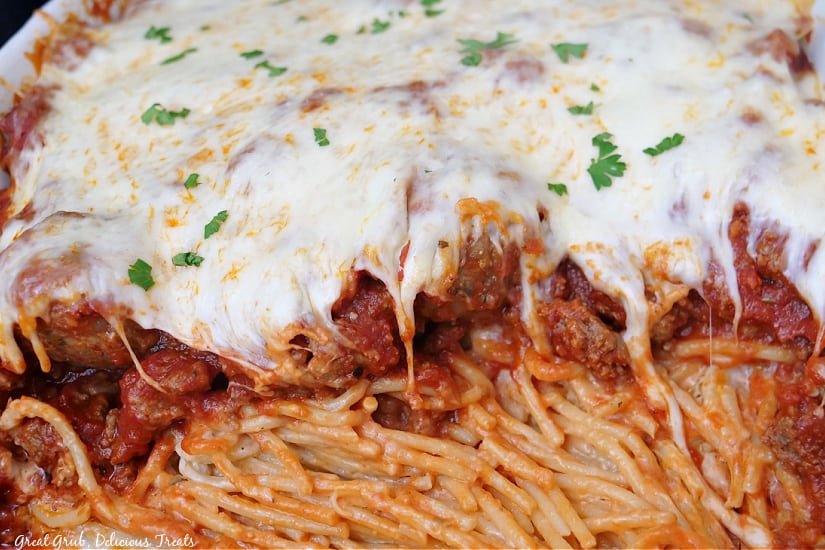A casserole dish with baked spaghetti and meatballs in it.