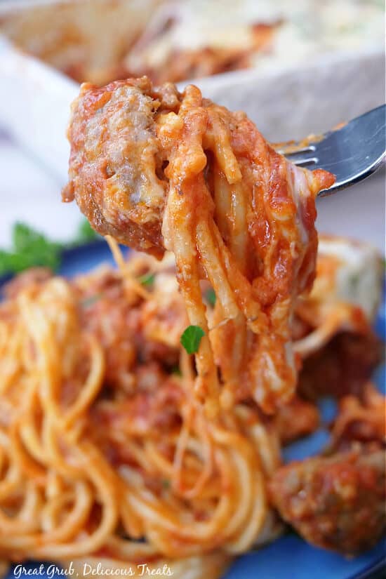 A forkful of cheesy spaghetti with a meatball on it.