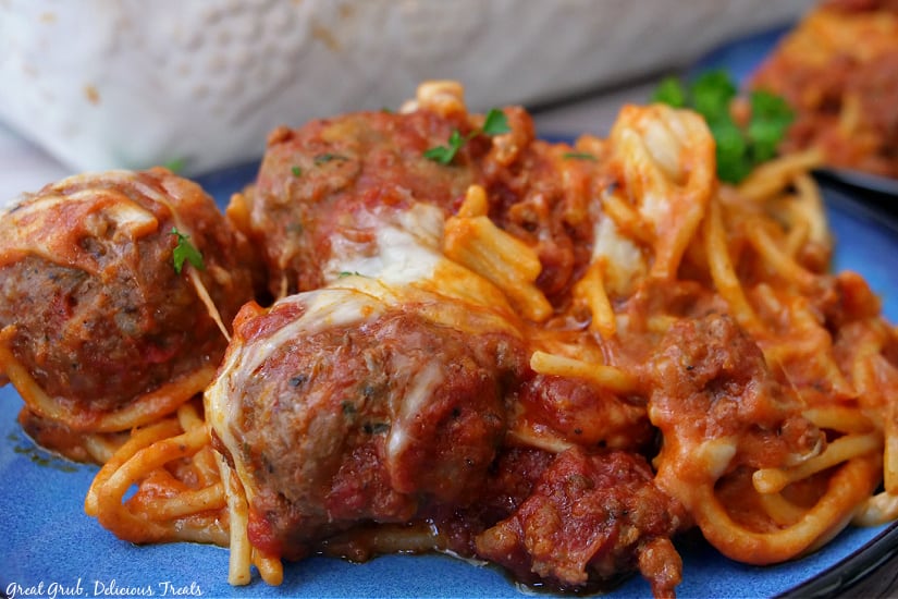 A serving of cheesy spaghetti and meatballs on a blue plate.