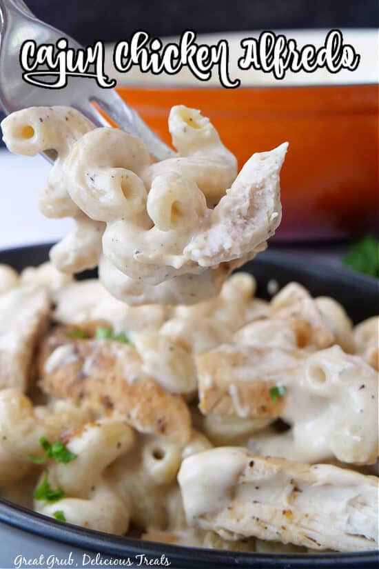 A close up of a bite of creamy pasta and chicken on a fork.