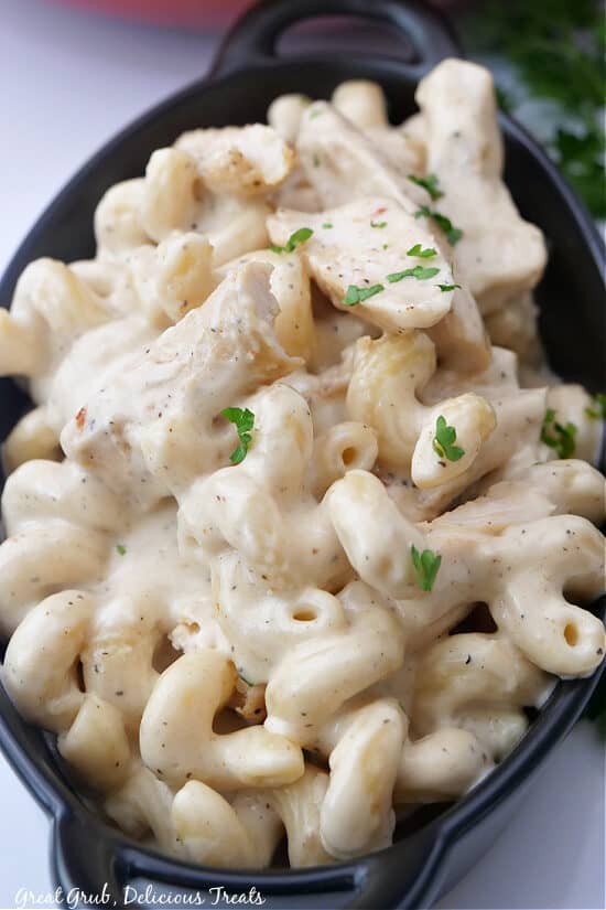 A black bowl with chicken alfredo pasta in it.