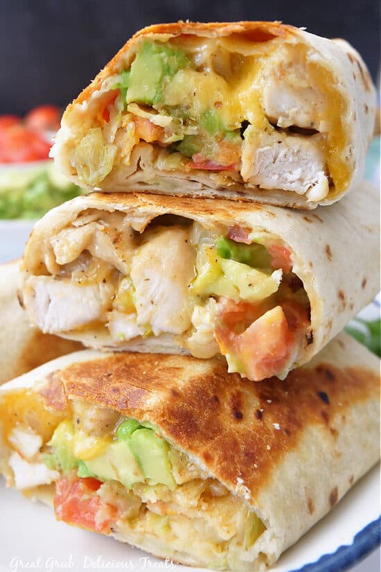 Three chicken burritos stacked on top of each other showing the inside ingredients of each burrito.