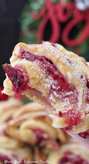 A close up of a cranberry cream cheese puff pastry with a bite taken out of it.