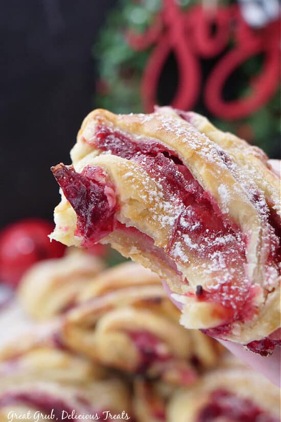 A close up of a cranberry puff pastry with a bite taken out of it.