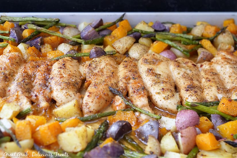 A sheet pan with chicken and vegetables on it after being pulled from the oven.