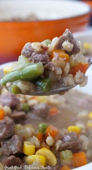 A horizonal photo of beef and barley soup with vegetables.