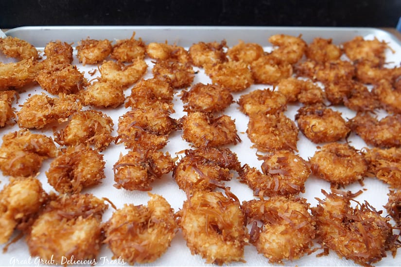 A baking sheet with cooked coconut shrimp on it.