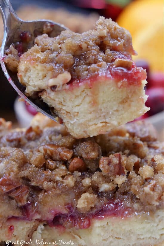A close up of a spoon with a bite of a bread pudding muffin on it.