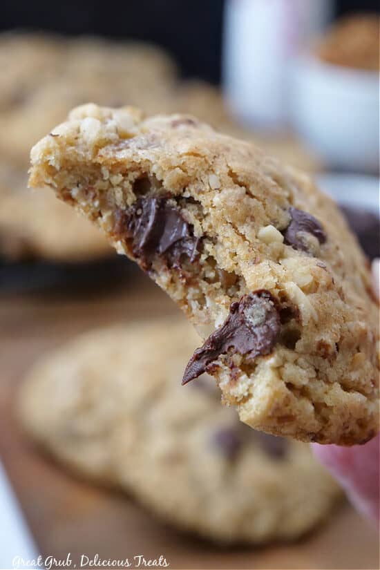 A close up of a chocolate chip cookie with a bite taken out of it.