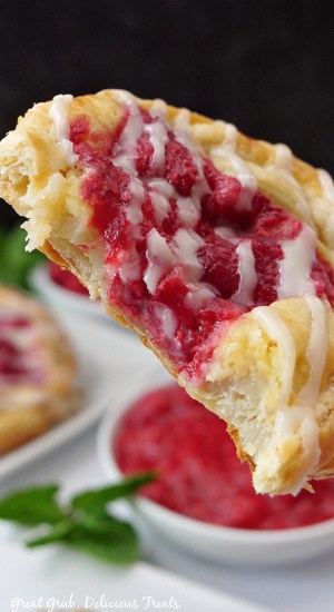 A close up of a raspberry Danish with a bite taken out of it.