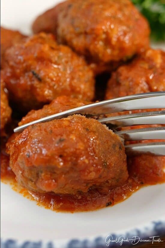 A close up of a meatball being cut in half with a fork.