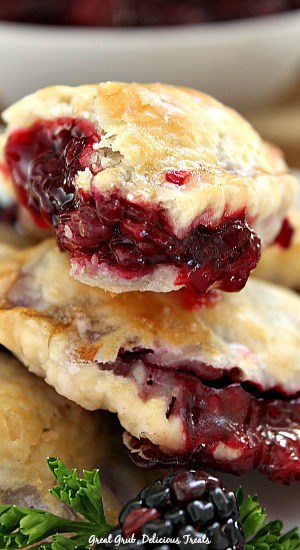 A close up of a couple blackberry hand pies showing the filling in one of them after a bite was taken.