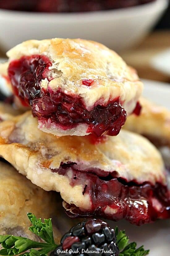 A couple of hand pies with the blackberry filling oozing out of one of them after a bite was taken.