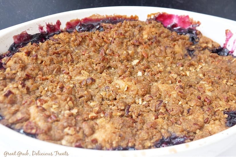A white oval baking dish with blueberry cobbler.