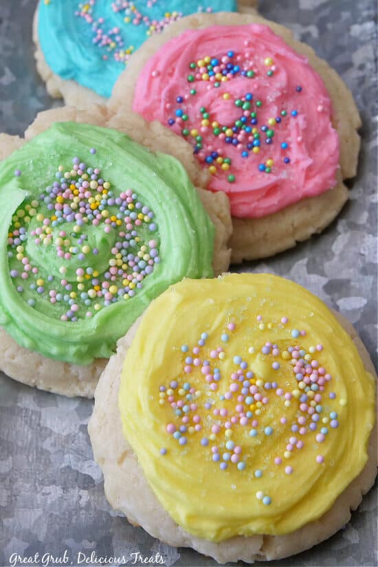 A sliver tray with four pastel frosted sugar cookies on it.
