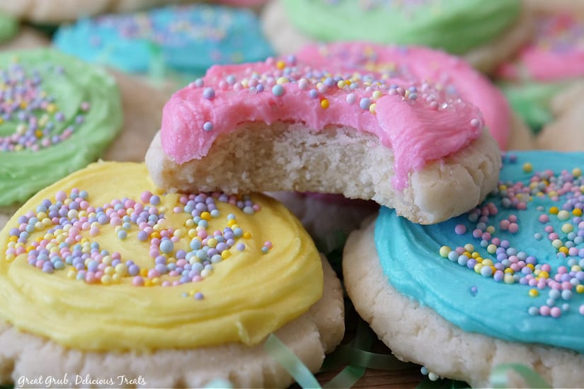 A close up of pastel frosted Easter Sugar Cookies with a bite taken out of one of them.