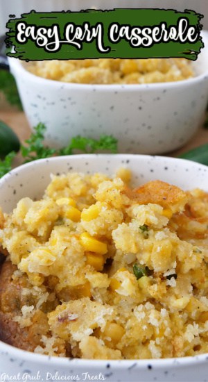 A white bowl with black specks filled with a serving of corn casserole.