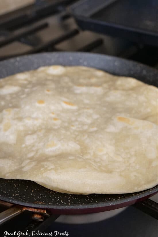 A flour tortilla being cooked in a pan.