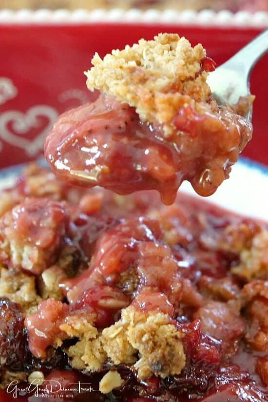 A close up of a spoonful of strawberry crisp.