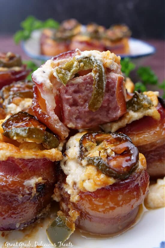 A close up photo of some bacon wrapped sausage bites with cream cheese mixture and jalapenos on them.