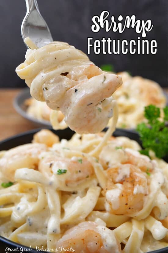 A fork with a bite of shrimp and fettuccine pasta on it.
