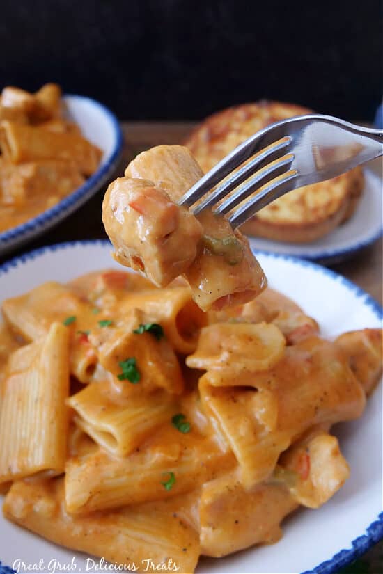 A bite of chicken and pasta on a fork.