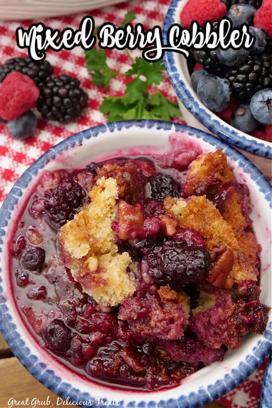 An overhead shot of a small bowl of cobbler with mixed berries in a small bowl in the background.