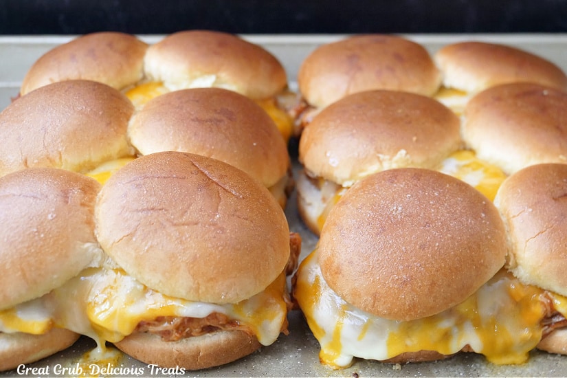a baking sheet with 12 chicken sliders after being removed from the oven.