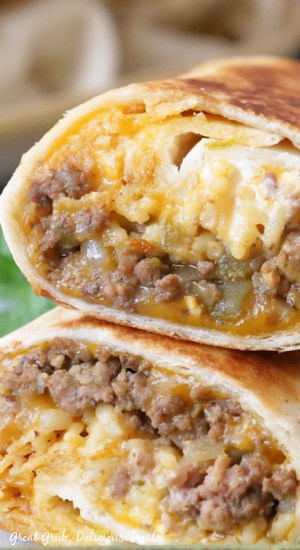 A close up of a cheesy double beef burrito cut in half.