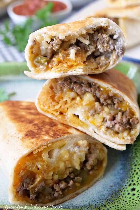 A stack of three beef burritos stacked on each other.