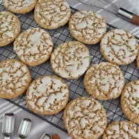 A wire rack with 15 iced oatmeal cookies on it.