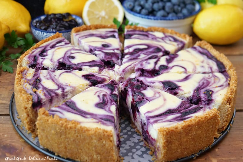 A horizontal photo of lemon blueberry cheesecake that has been sliced and is on the base of the springform pan.