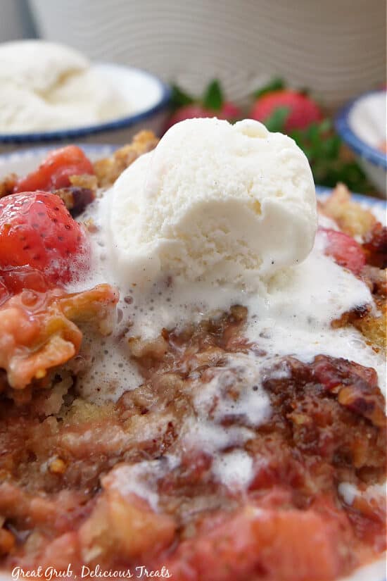 A close up of a serving of cobbler with a scoop of vanilla ice cream on it that has started to melt.