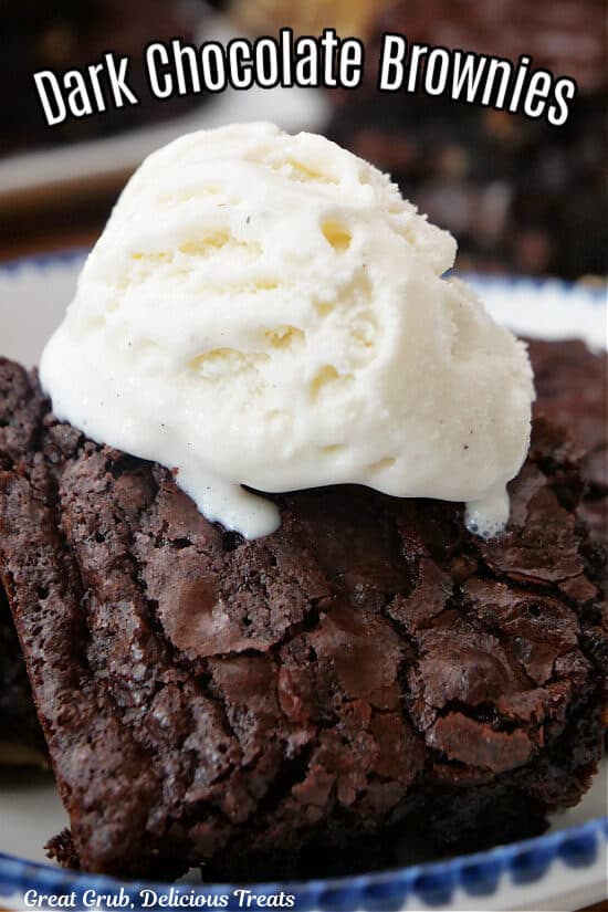 A close up photo of a chocolate brownie with a scoop of vanilla ice cream on top.