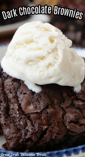 A close up of a dark chocolate brownie with vanilla ice cream on top.