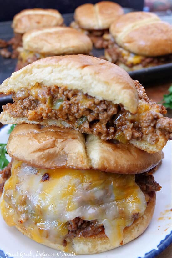 A close up of a bun filled with ground beef and cheese placed on top of another sandwich.