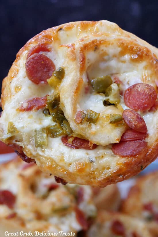 A close up of a pizza pinwheels showing the mini pepperonis and diced jalapenos.