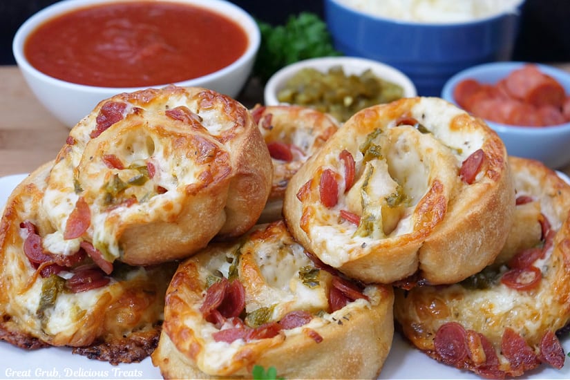 A horizontal photo of a white plate with six pepperoni pizza roll ups on it.
