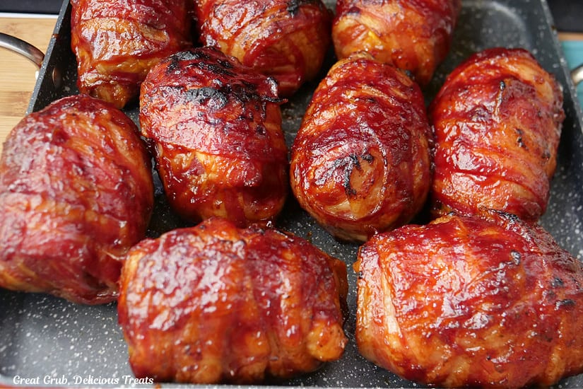 A baking tray with nine bacon wrapped chicken bombs on it.