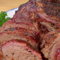 Sliced smoked tri tip on a white plate.