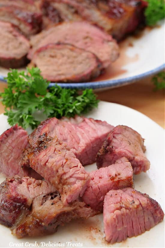 A close up of some bite-size pieces of smoked tri tip on a white plate.