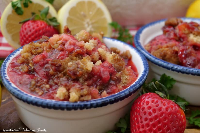A horizontal photo of two white bowls filled with strawberry cobbler with brown sugar pecan crust.
