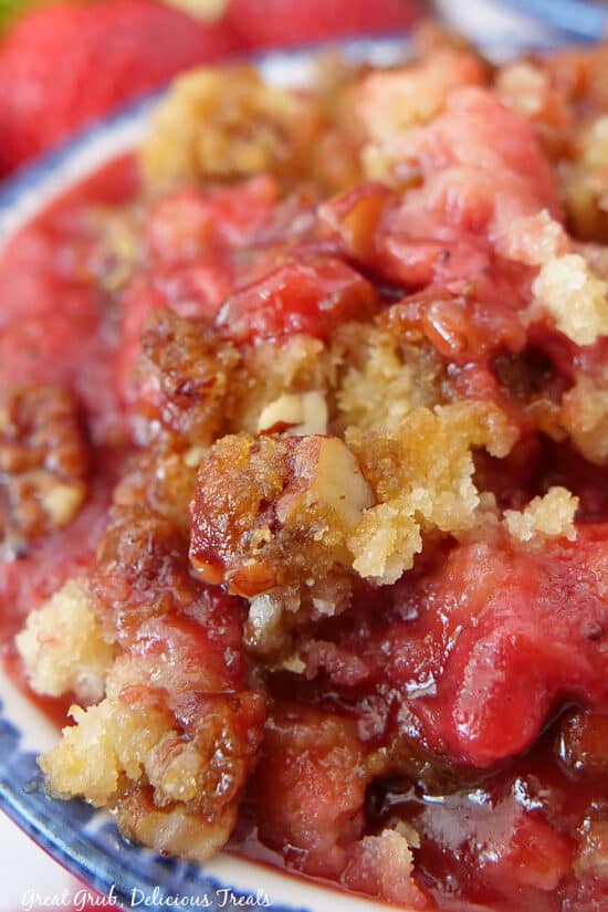 A super close up photo of strawberry cobbler in a white bowl with blue trim.